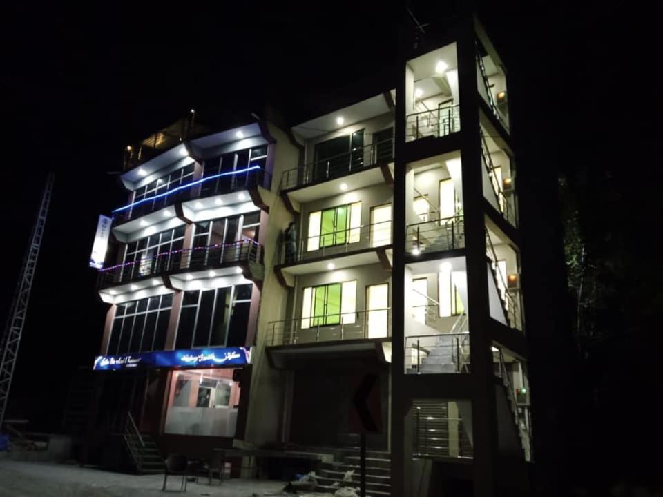 a tall building with lit up windows at night at Golden Bite Hotel and Restaurant in Alīābād