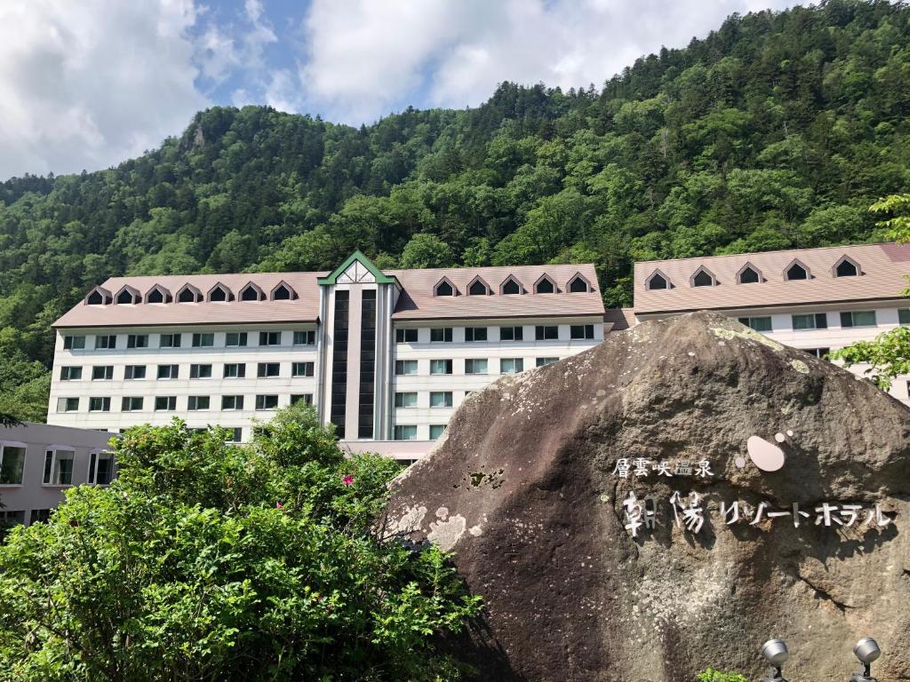 a large white building in front of a mountain at Choyo Resort Hotel in Kamikawa