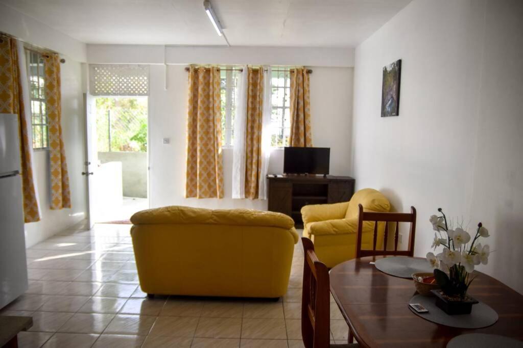 uma sala de estar com um sofá amarelo e uma mesa em Green Castle Apartment#3 in City of Roseau em Roseau