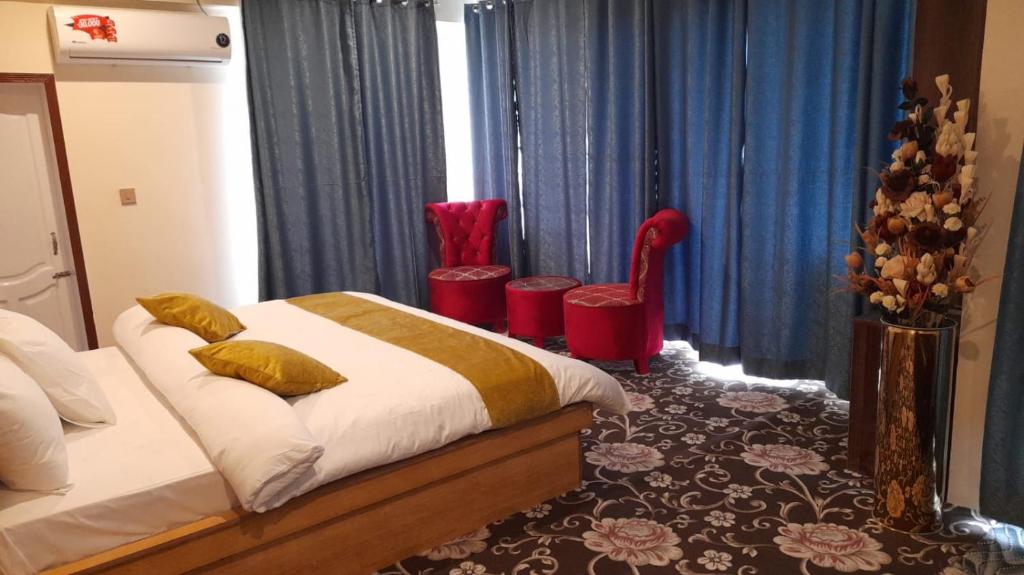 a bedroom with a bed and two red chairs at Hunza Grand Motel in Alīābād