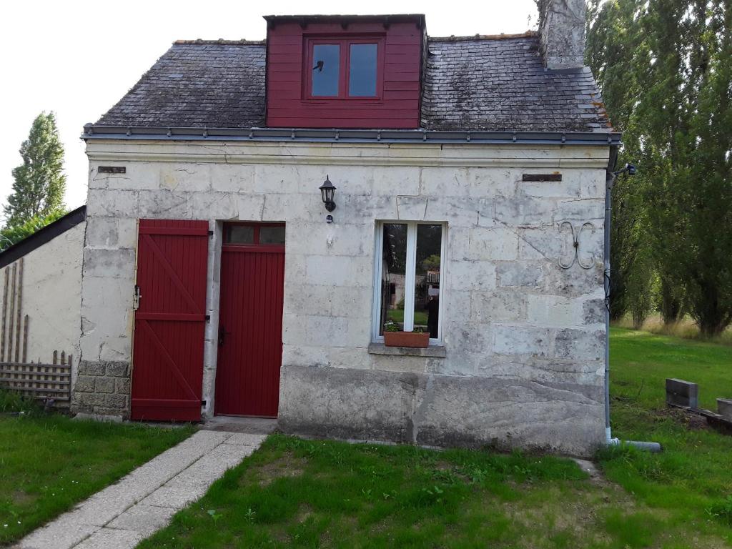 ein kleines Haus mit einer roten Tür und einem Fenster in der Unterkunft Cottage La Halouère in Saint-Philbert-du-Peuple