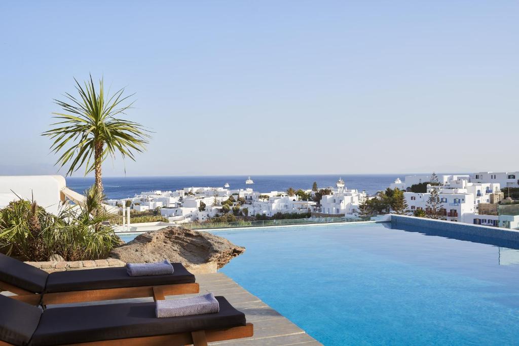a pool with chairs and a view of the ocean at Mr & Mrs White Mykonos in Platis Gialos