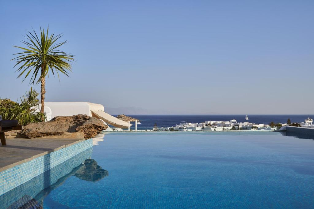 a swimming pool with a palm tree next to a resort at Mr & Mrs White Mykonos in Platis Gialos