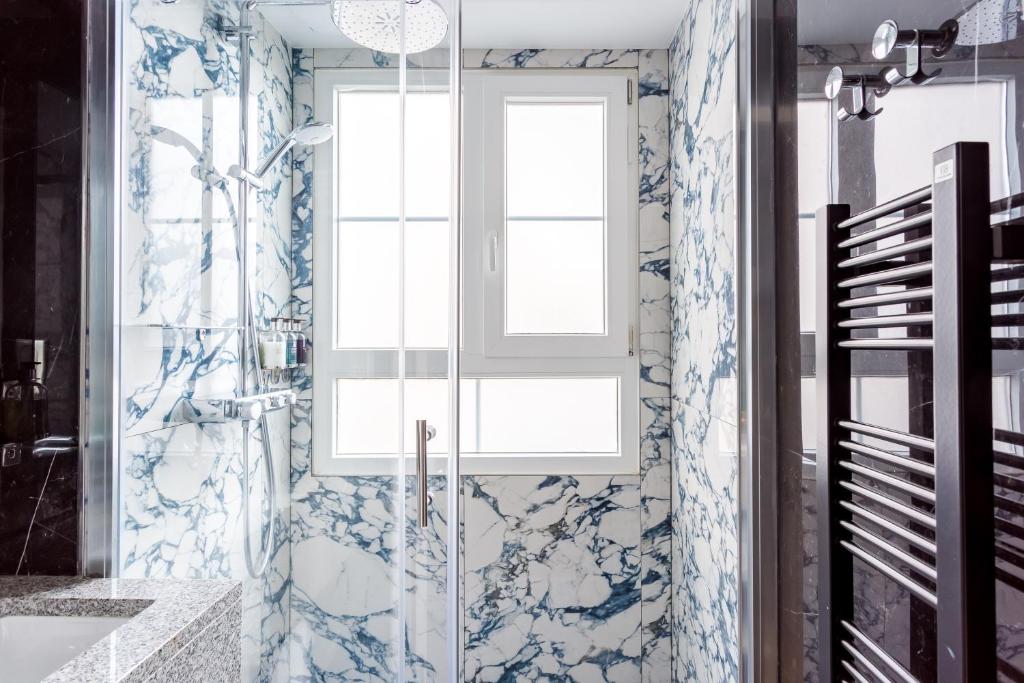 a bathroom with a shower with blue and white tiles at Luxury 2 Bedroom 2,5 Bathroom Apartment - Champs Elysees in Paris