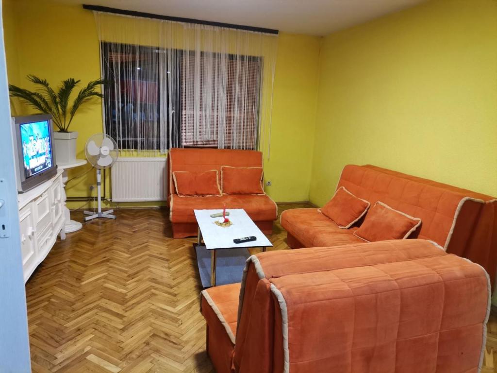 a living room with orange furniture and a tv at Kuca za odmor Simic in Vrnjačka Banja