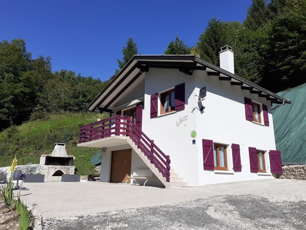 ein weißes Haus mit lila Fenstern und einer Treppe in der Unterkunft Gîte de campagne in Rosureux