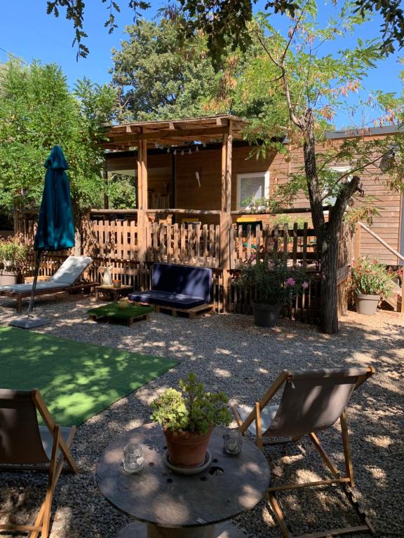 un patio trasero con una mesa y sillas y una valla en le clos du bonheur, en Le Pradet