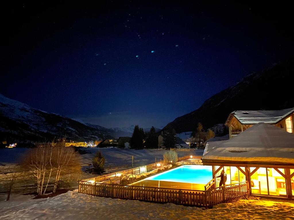 una piscina nella neve di notte di Appartements de la Chamoissière a Le Monêtier-les-Bains