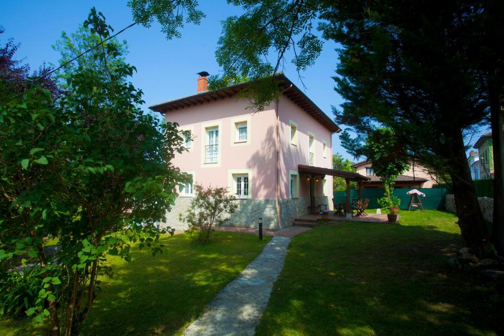 une grande maison rose avec une pelouse dans l'établissement Villa Mercedes, à Piloña