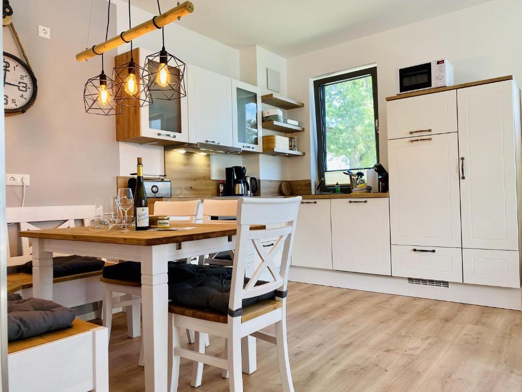 a kitchen with a wooden table and white cabinets at Parkvillen Carlota und Candela Baabe in Baabe