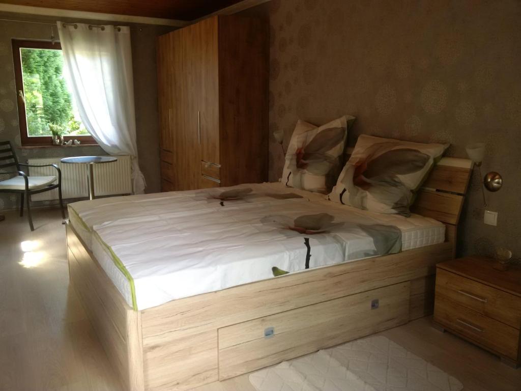 Un dormitorio con una gran cama de madera con sábanas blancas. en Haus Bergrose, en Busenborn