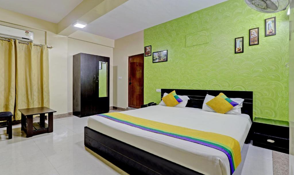 - une chambre avec un grand lit et un mur vert dans l'établissement Itsy By Treebo - Palm Emirates, à Bangalore