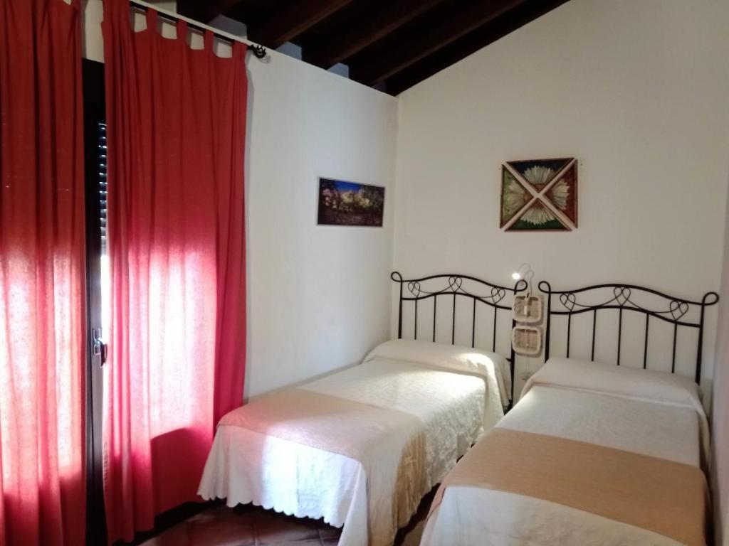 2 camas en una habitación con cortinas rojas en La Mina Rural Casas con encanto, en La Isabel