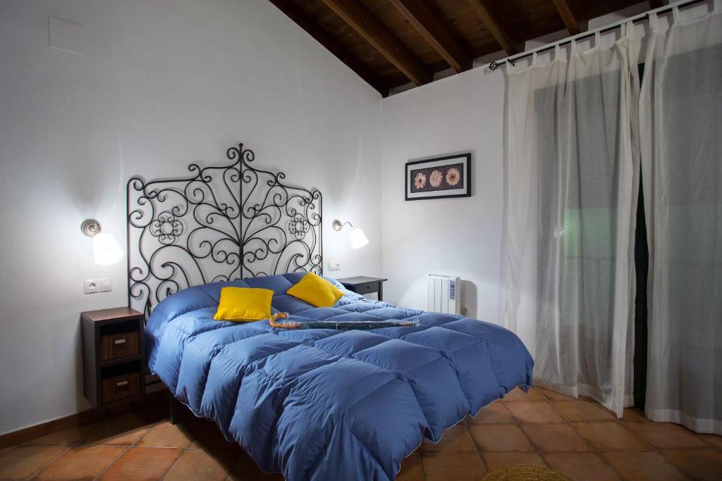 Dormitorio con cama con edredón azul y almohadas amarillas en La Mina Rural Casas con encanto, en La Isabel