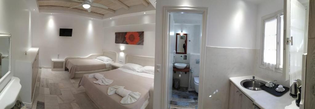 a white bathroom with a tub and a sink at Ostria Hotel in Agios Prokopios