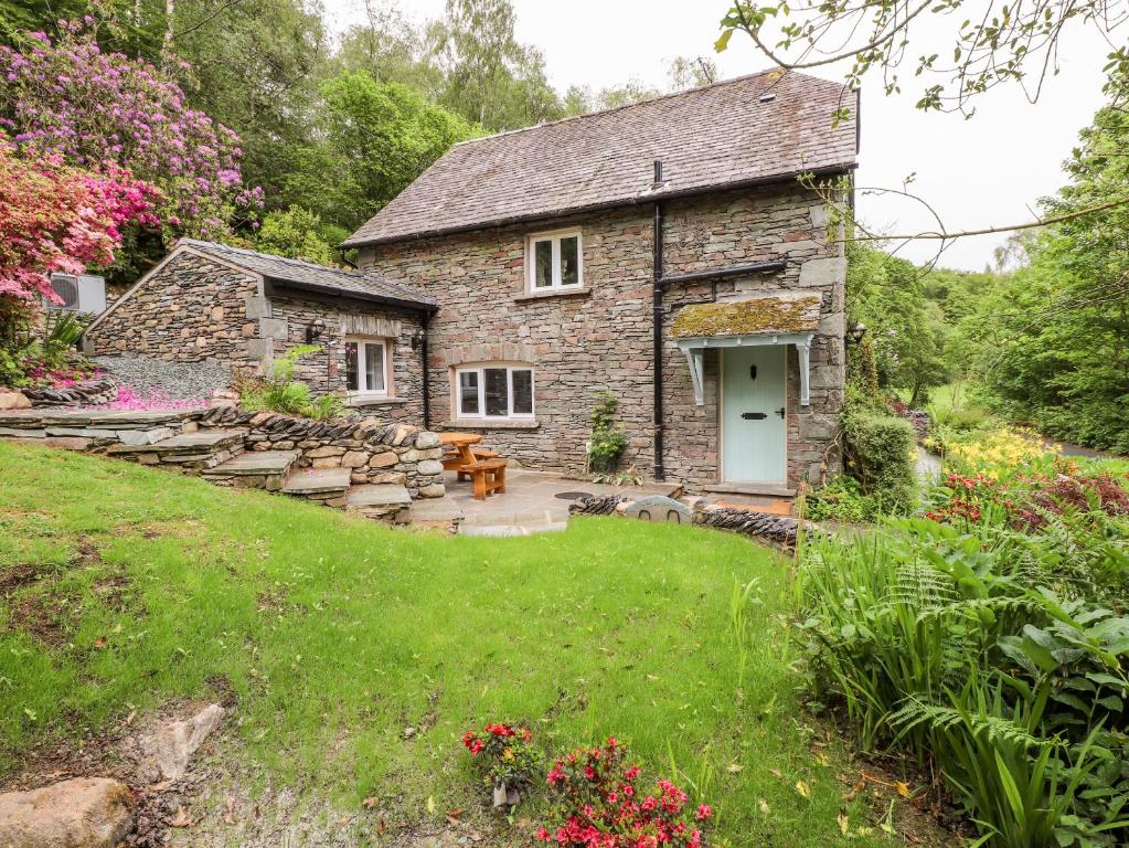 une maison en pierre avec un jardin et une pelouse dans l'établissement Silverthwaite Cottage, à Ambleside