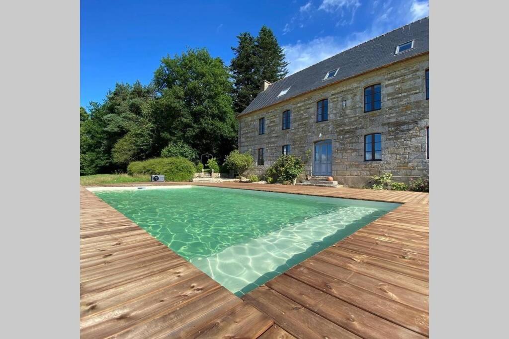 uma casa com piscina ao lado de um edifício em La Lande du Rest - Le Quillio Magnifique ancienne ferme de notables avec piscine chauffée em Le Quillio