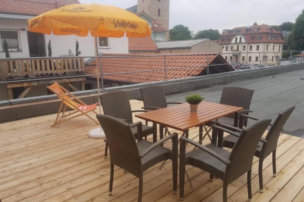 een houten tafel met stoelen en een parasol op een dak bij Wohnen am Schloss, Herzog in Sondershausen