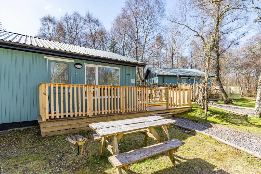 uma mesa de piquenique e banco em frente a uma cabine em Bracken Lodge 7 with Hot Tub em Belladrum