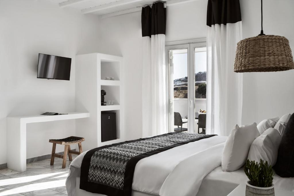 a white bedroom with a bed and a window at Mr & Mrs White Mykonos in Platis Gialos