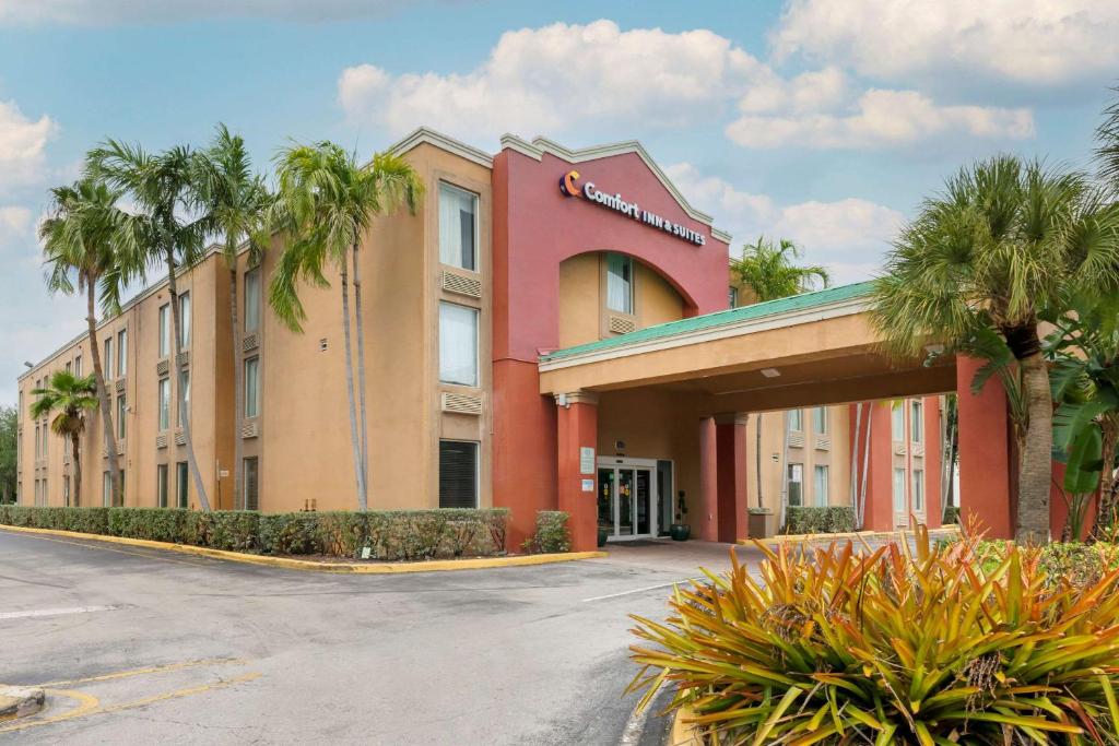 a hotel with palm trees in front of a building at Comfort Inn & Suites Fort Lauderdale West Turnpike in Fort Lauderdale