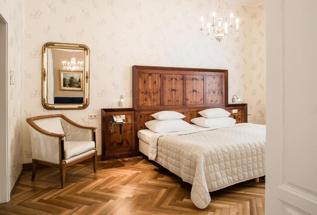 um quarto com uma cama, uma cadeira e um espelho em Palais-Hotel Erzherzog Johann em Graz