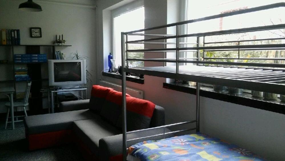 a room with a bunk bed and a couch and a television at Apartament Pod Kukułką in Kłodzko