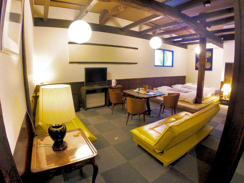 una camera con un letto e un tavolo con un divano giallo di Rickshaw inn a Takayama