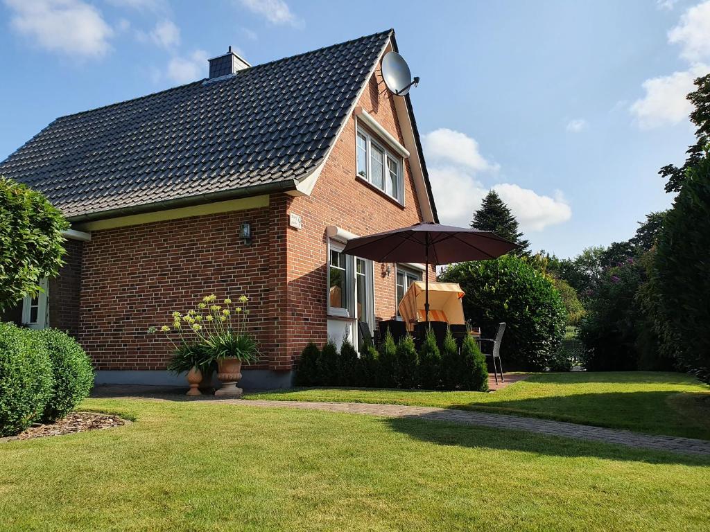 a brick house with an umbrella in the yard at Ferienhaus - Dorfperle Borstel in Borstel