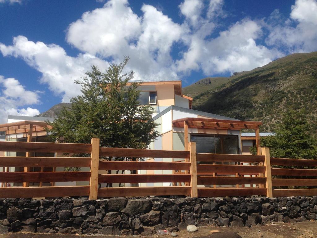 a house with a fence in front of a mountain at Refugio Ecobox Andino in Las Trancas