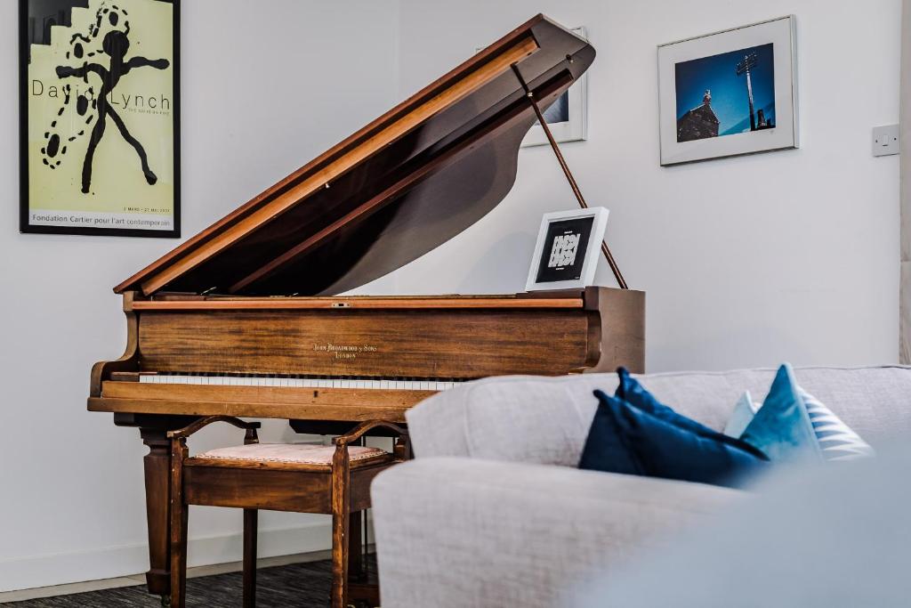 un piano en una sala de estar junto a un sofá en Host & Stay - The Musician's Apartment with Grand Piano, en Liverpool