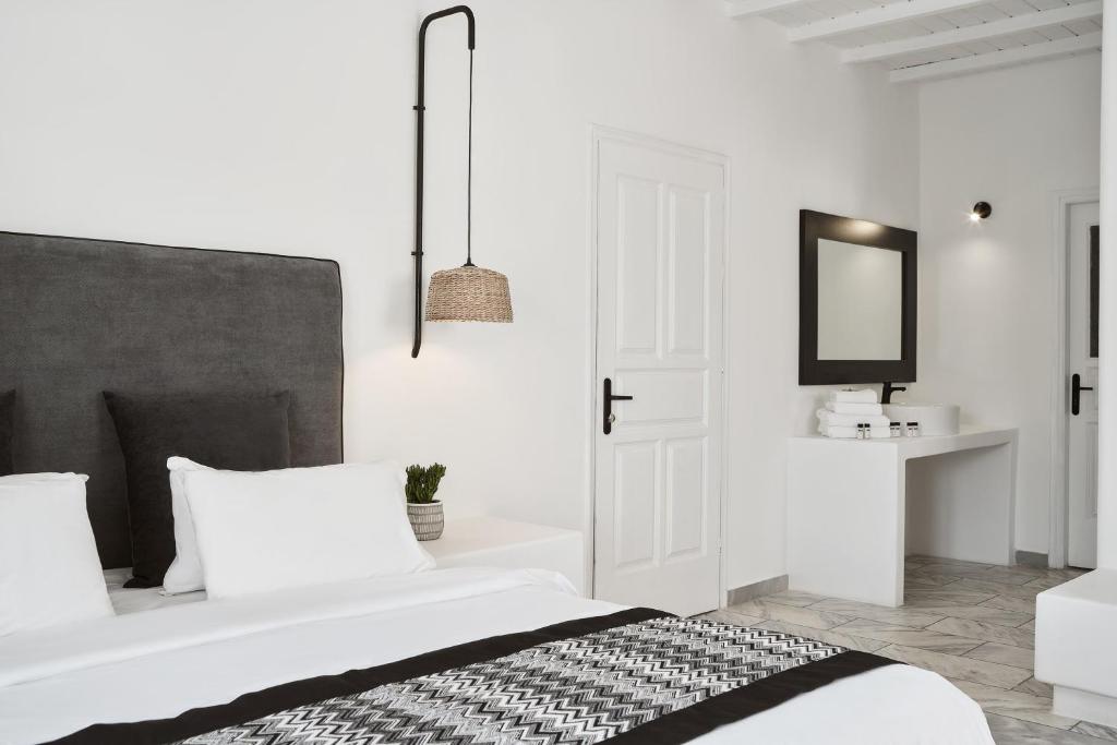 a white bedroom with a bed and a mirror at Mr & Mrs White Mykonos in Platis Gialos