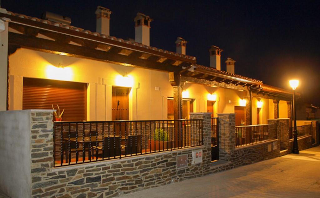 una casa con balcón por la noche con luces en Apartamentos Rurales El Calama, en Zarza de Granadilla