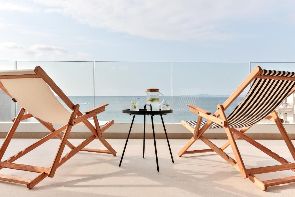 duas cadeiras de madeira e uma mesa em frente a uma janela em ECO-APARTMENTS LA MARINEDA em Roses