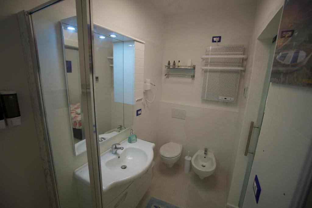 Un baño con lavabo, inodoro y ducha. en Ambra Apartment, en Isquia