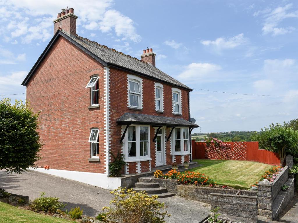 a red brick house with white windows and a yard at Silver Crooks in Holsworthy