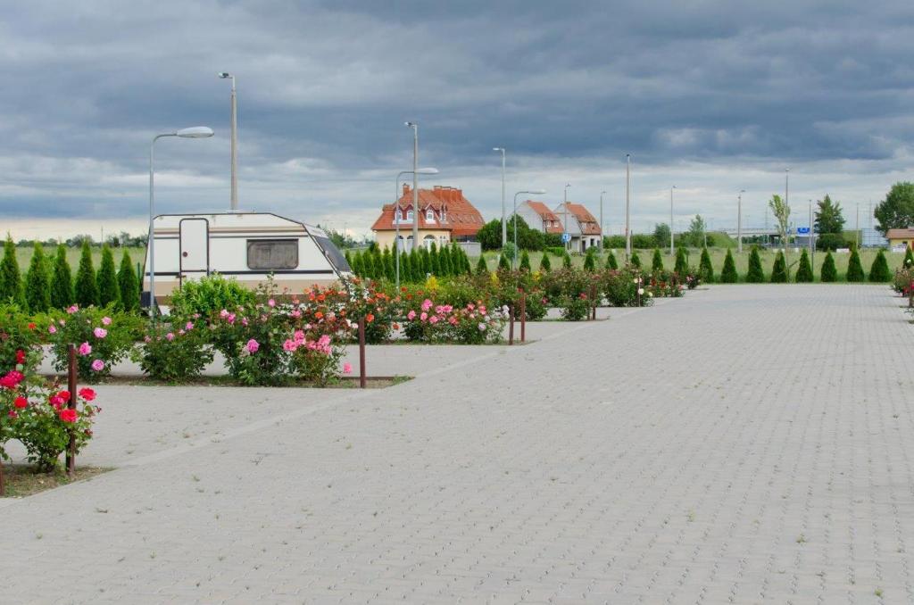 a parking lot with a camper and some flowers at Hotel Rózsa Csárda Bungalow & Caravan Park in Hegyeshalom