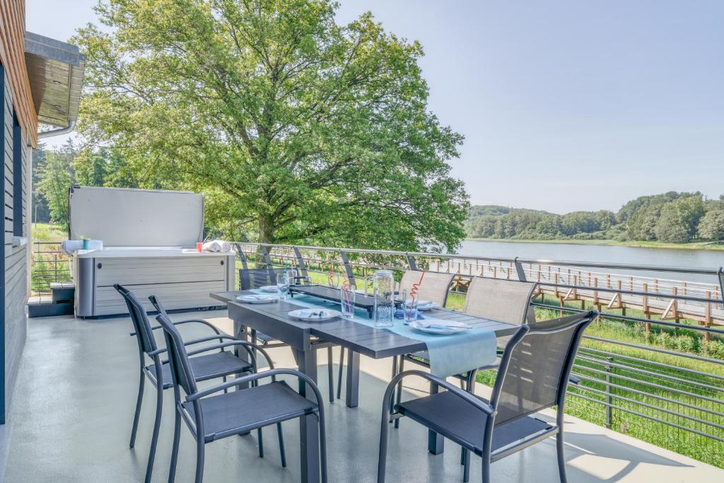 einen Tisch und Stühle auf einem Balkon mit Blick auf das Wasser in der Unterkunft Les Bambous in Sanchey