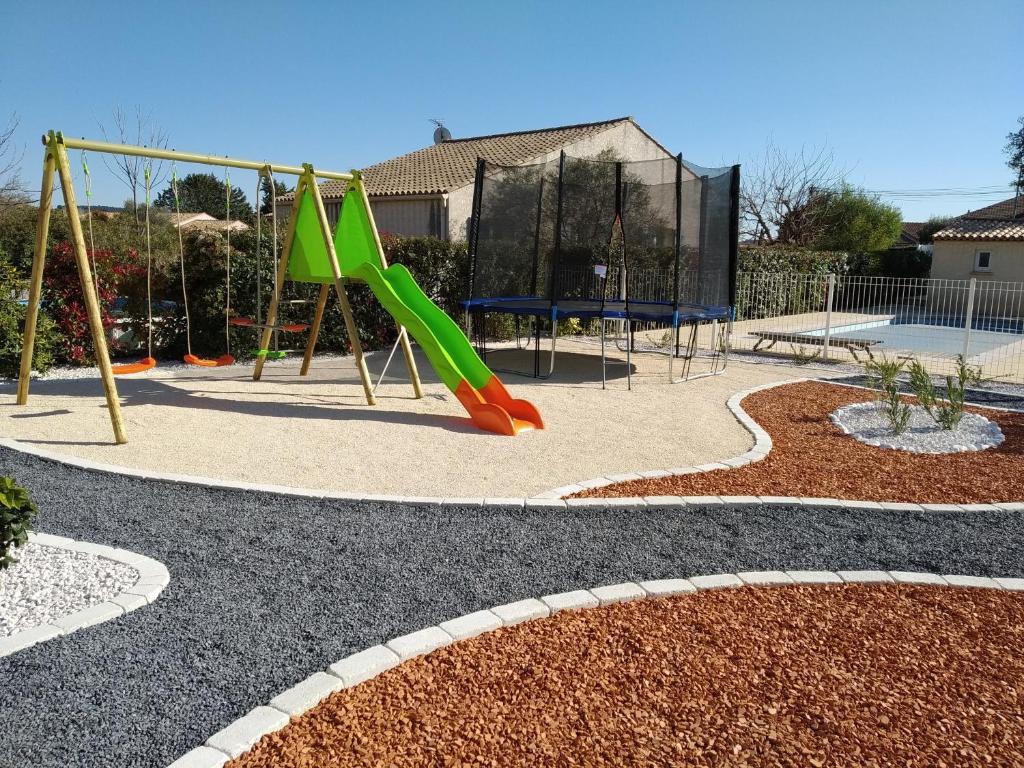 a playground with a green slide and swings at villa classée 4 étoiles avec piscine et boulodrome in Canet