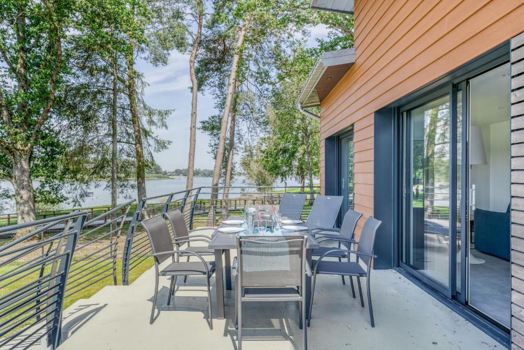 einen Tisch und Stühle auf einem Balkon mit Blick auf das Wasser in der Unterkunft Les Roseaux in Sanchey