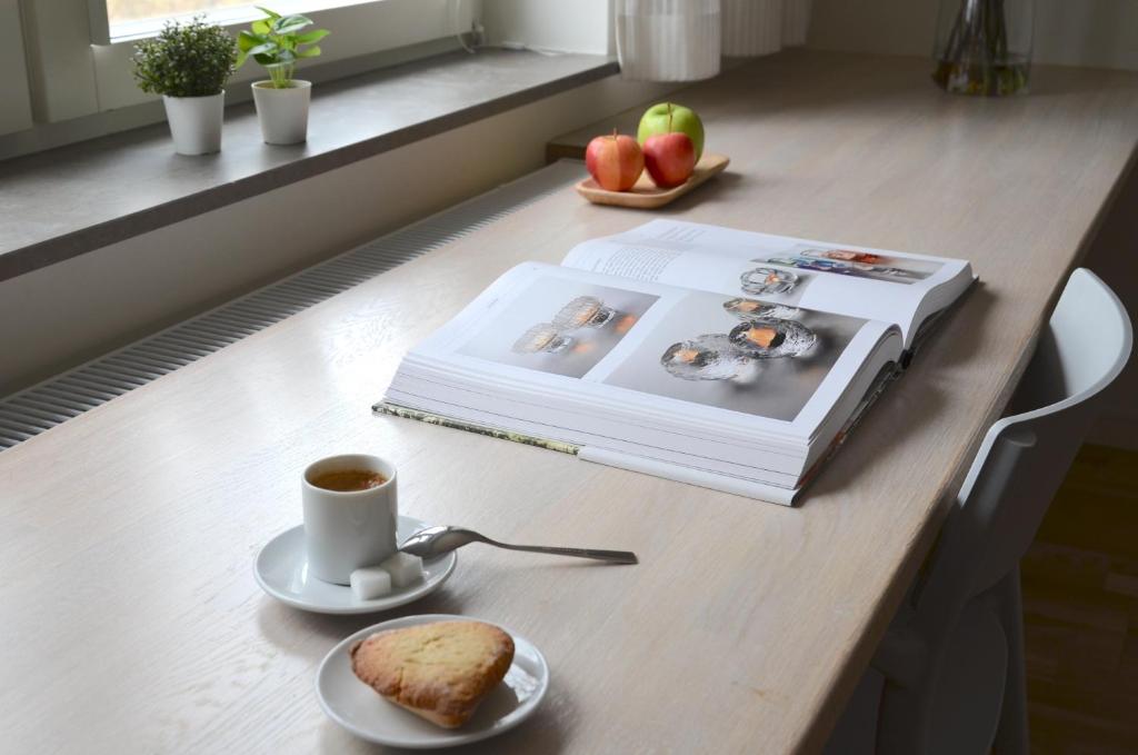 un livre, une tasse de café et une assiette de pain dans l'établissement Forskarhotellet, à Lund