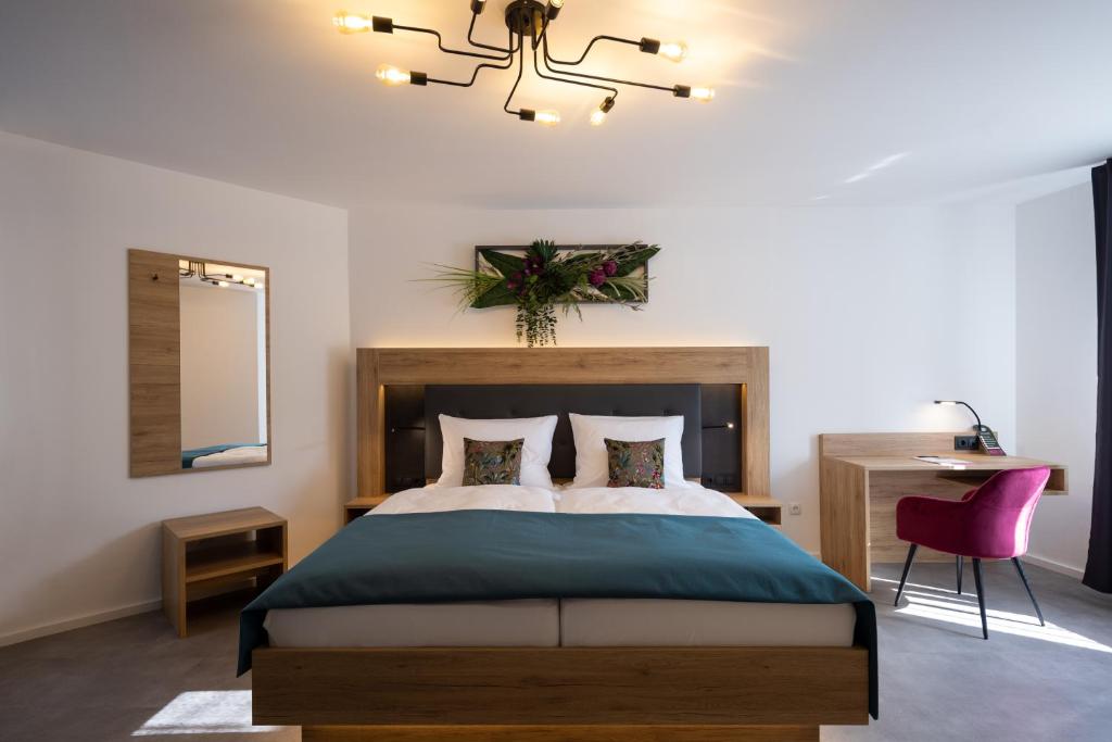 1 dormitorio con cama, espejo y silla en Bed and Breakfast - Homburg am Main, en Homburg