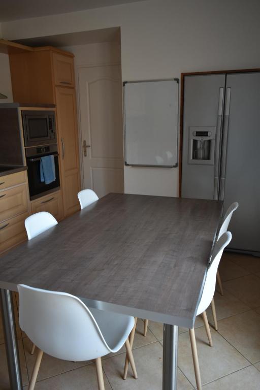 a kitchen with a table with white chairs and a refrigerator at villa classée 4 étoiles avec piscine et boulodrome in Canet
