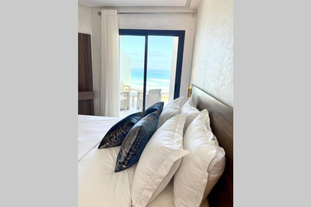 a bedroom with a bed with pillows and a window at Superbe appartement en front de mer haut standing in Kenitra