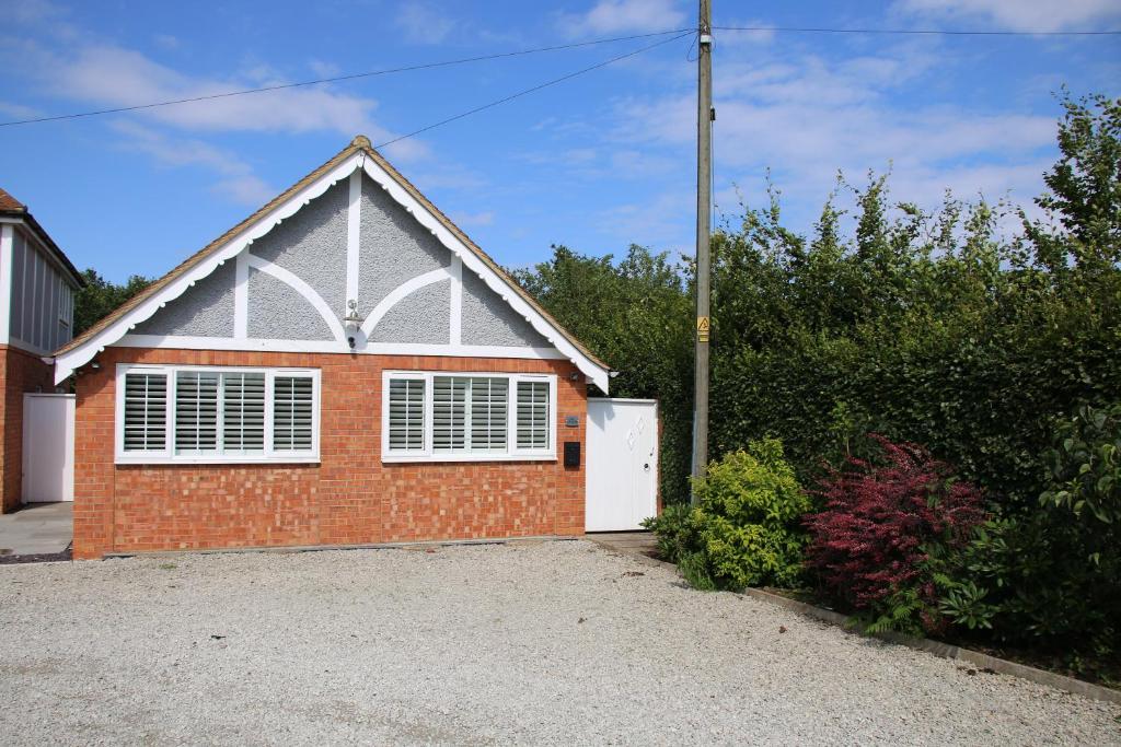 uma casa de tijolos vermelhos com uma garagem branca em Beautiful, 2 Bedroom Cottage em Selstead
