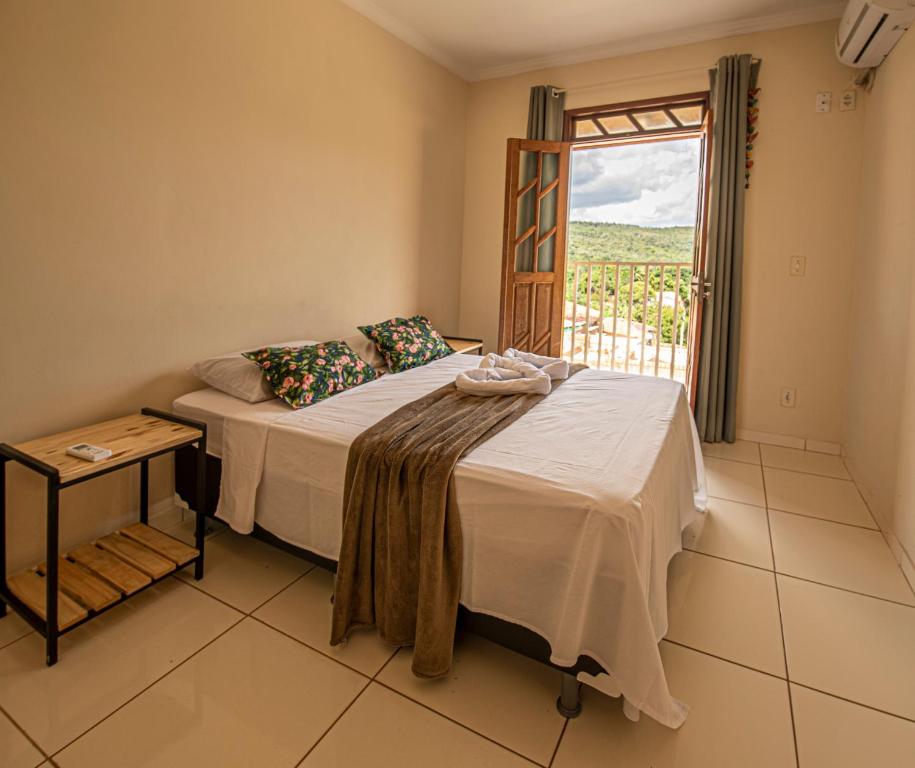 a bedroom with a bed with a window and a table at Village Funchal, Lençóis in Lençóis