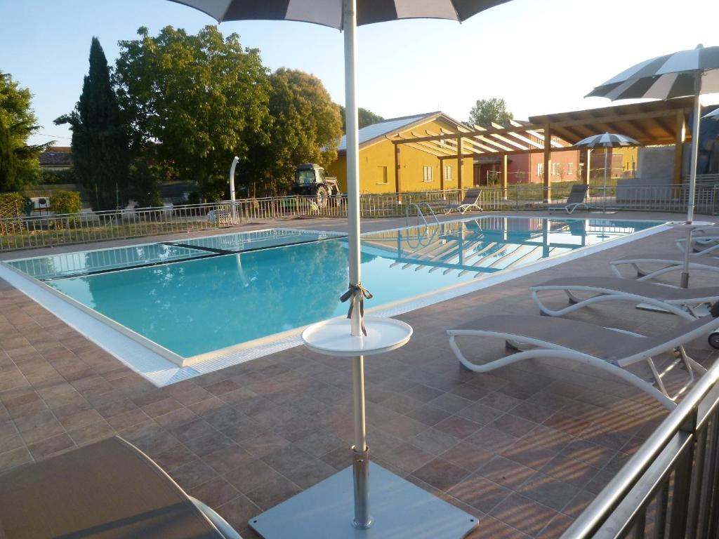 a pool with chairs and an umbrella next to it at Relais Villa Giulia in Bastia Umbra