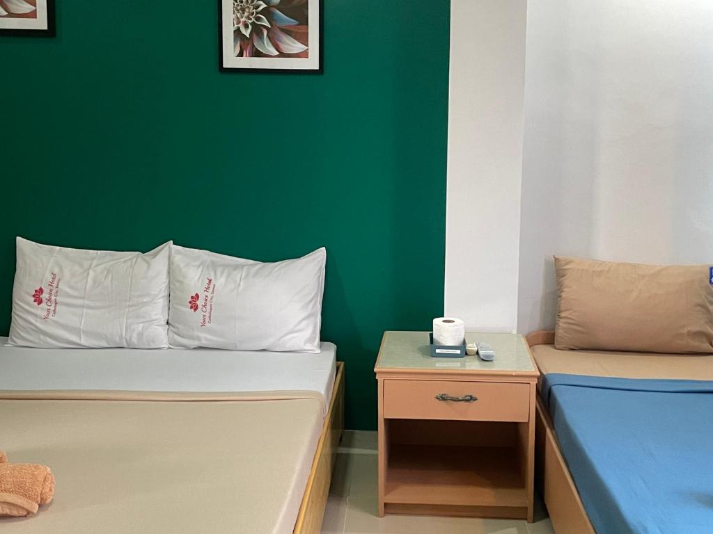 Habitación con 2 camas y pared verde. en Your Choice Hotel, en Catbalogan