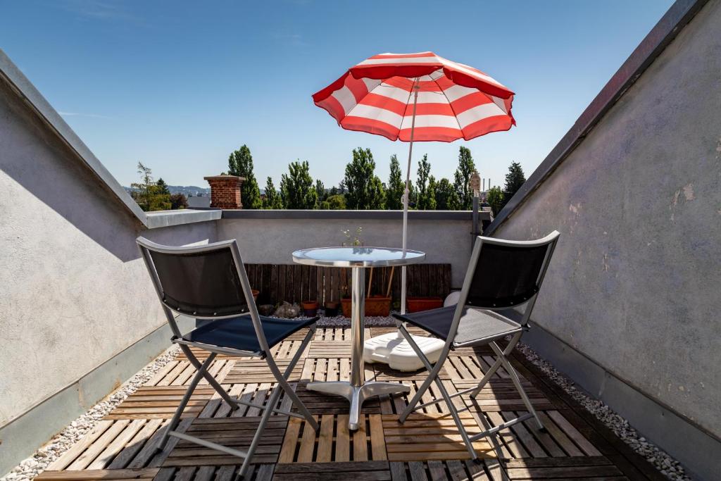 2 chaises et une table avec un parasol sur le balcon dans l'établissement Andreas' Dachwohnung mit Terrasse, à Graz