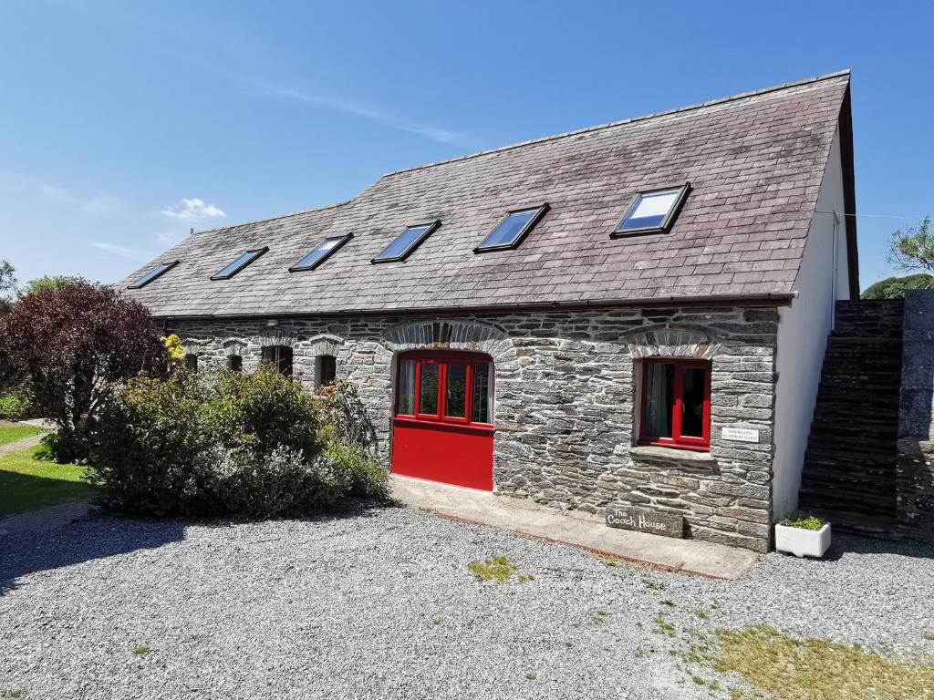a stone house with red doors and windows at Wellstone Cottages - Honey Coach House in Pembrokeshire